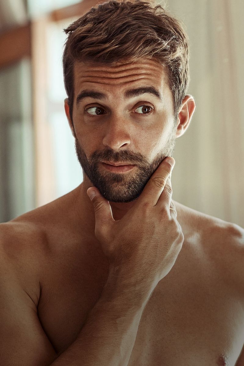 Man contemplating with hand on chin, indoors.